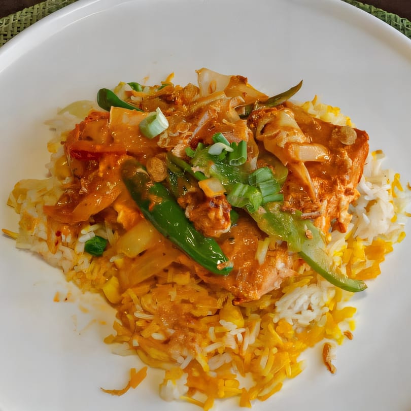 Atithi Restaurant's Bangladeshi salmon curry with green chilies, onions, and rice on a white plate.