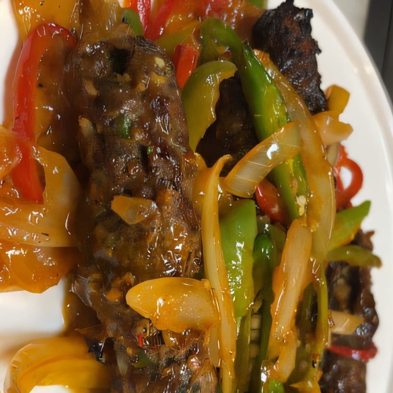 Close-up of Bangladeshi stir-fried beef with colorful bell peppers and onions in a rich sauce.